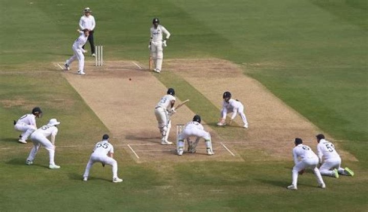 Can a fielder stand behind the bowler?